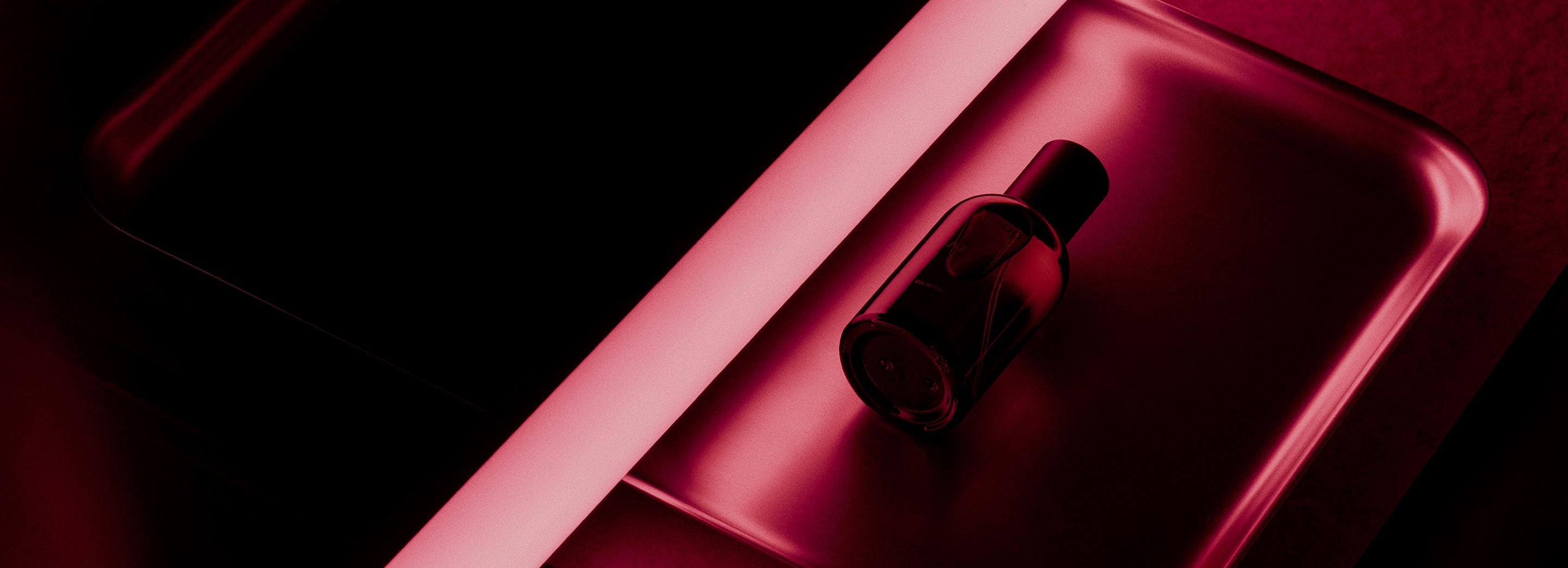 Aurner EDP bottle placed on a metal tray reflecting dark pink lights