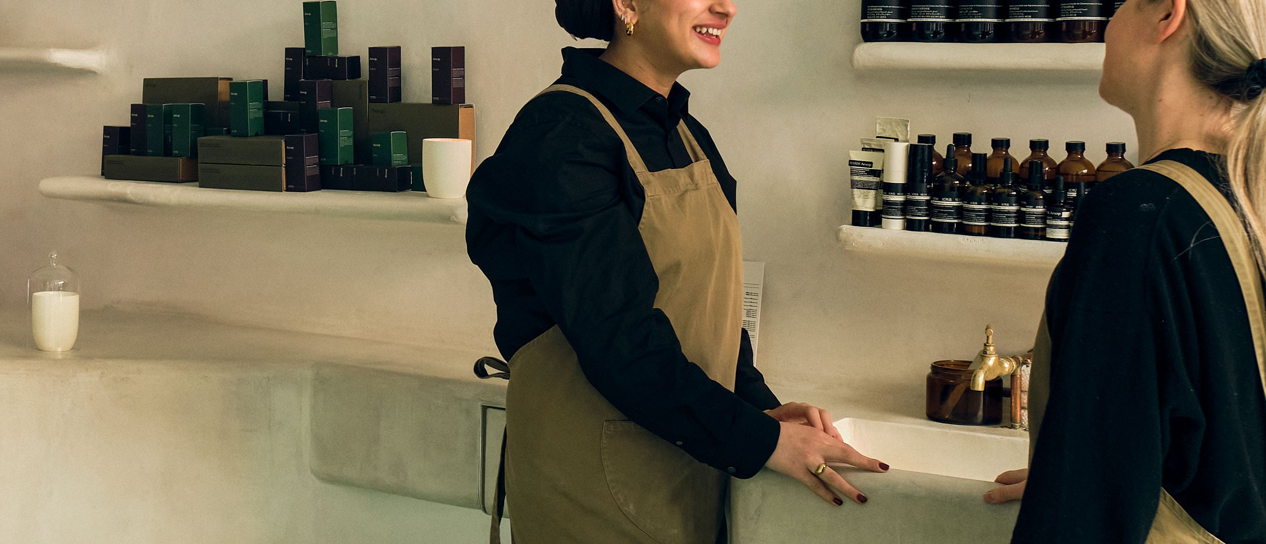 Two Aesop consultants enjoy a conversation next to an an in-store basin. 