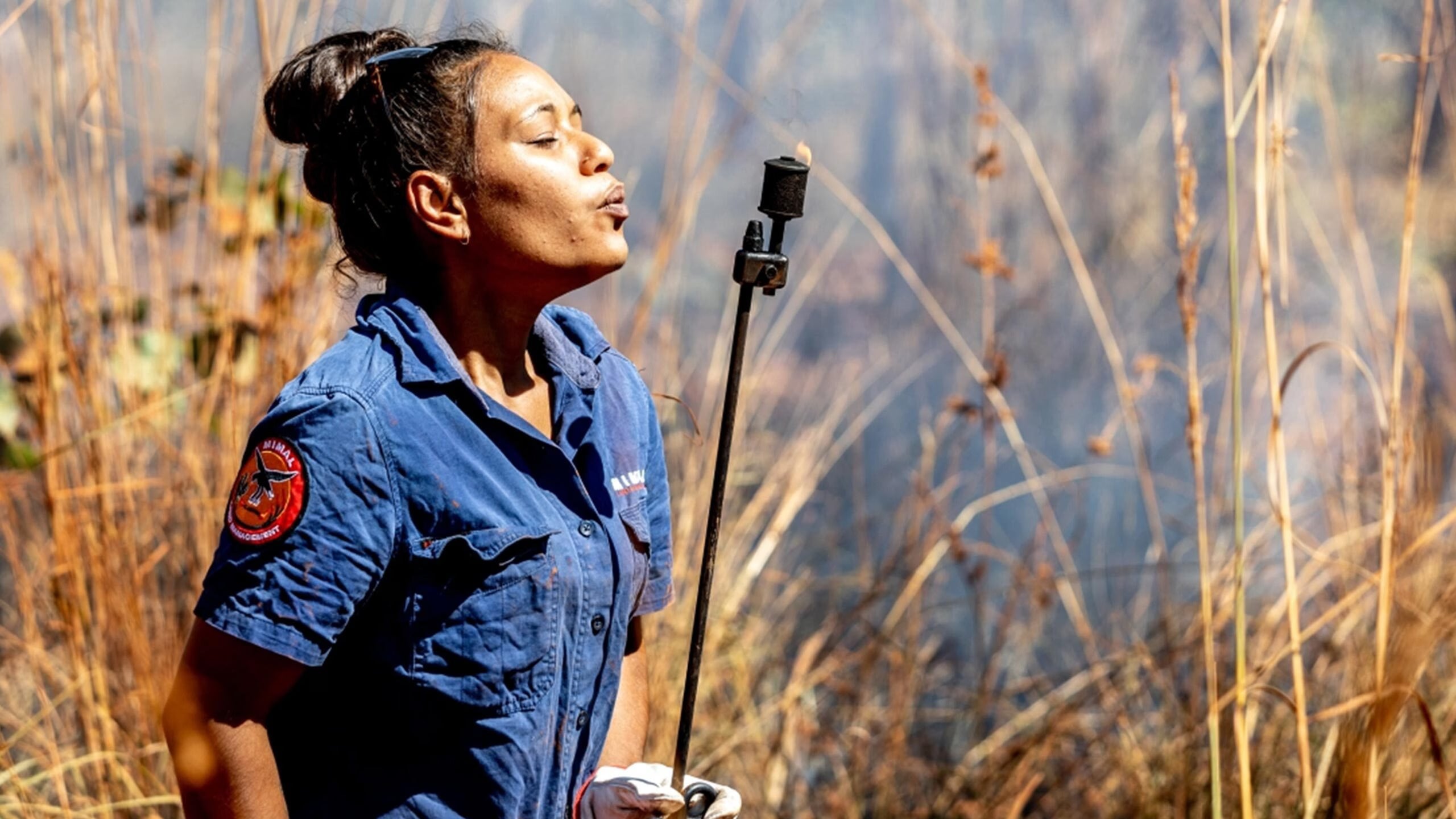 An individual holding a torch in a dry grass field