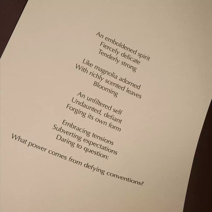 Curved cream page with printed verse against a dark brown background.