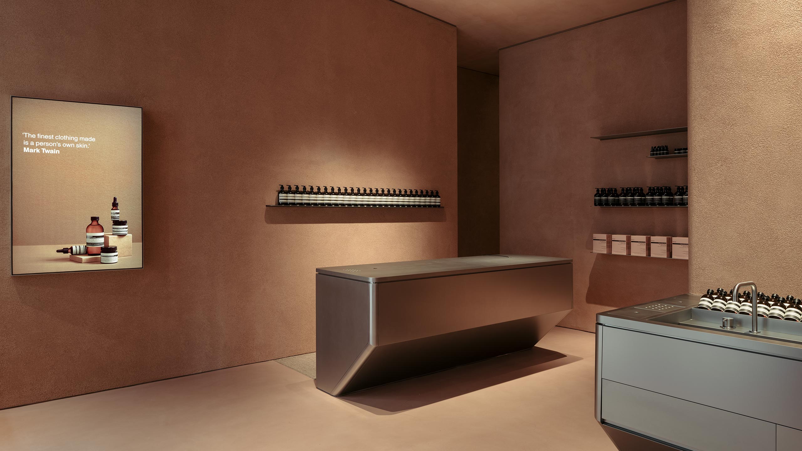 Stainless-steel basin and customer service counter that is juxtaposed against a natural terracotta-toned wall. 