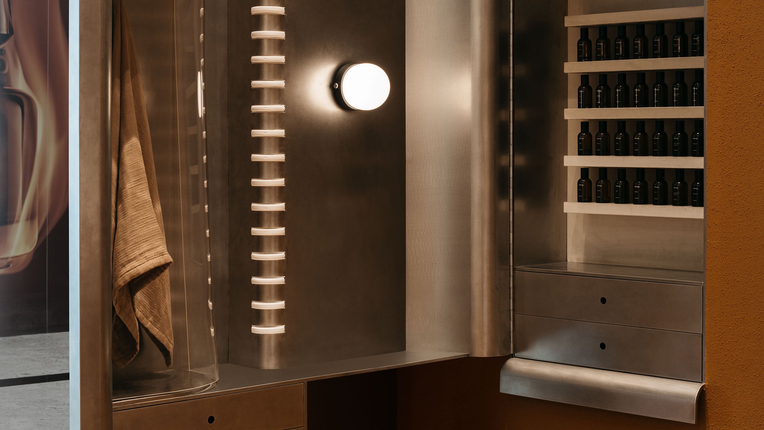 The polished metal tables as the reflective phone booths  are reimagined as a Fragrance Armoire.