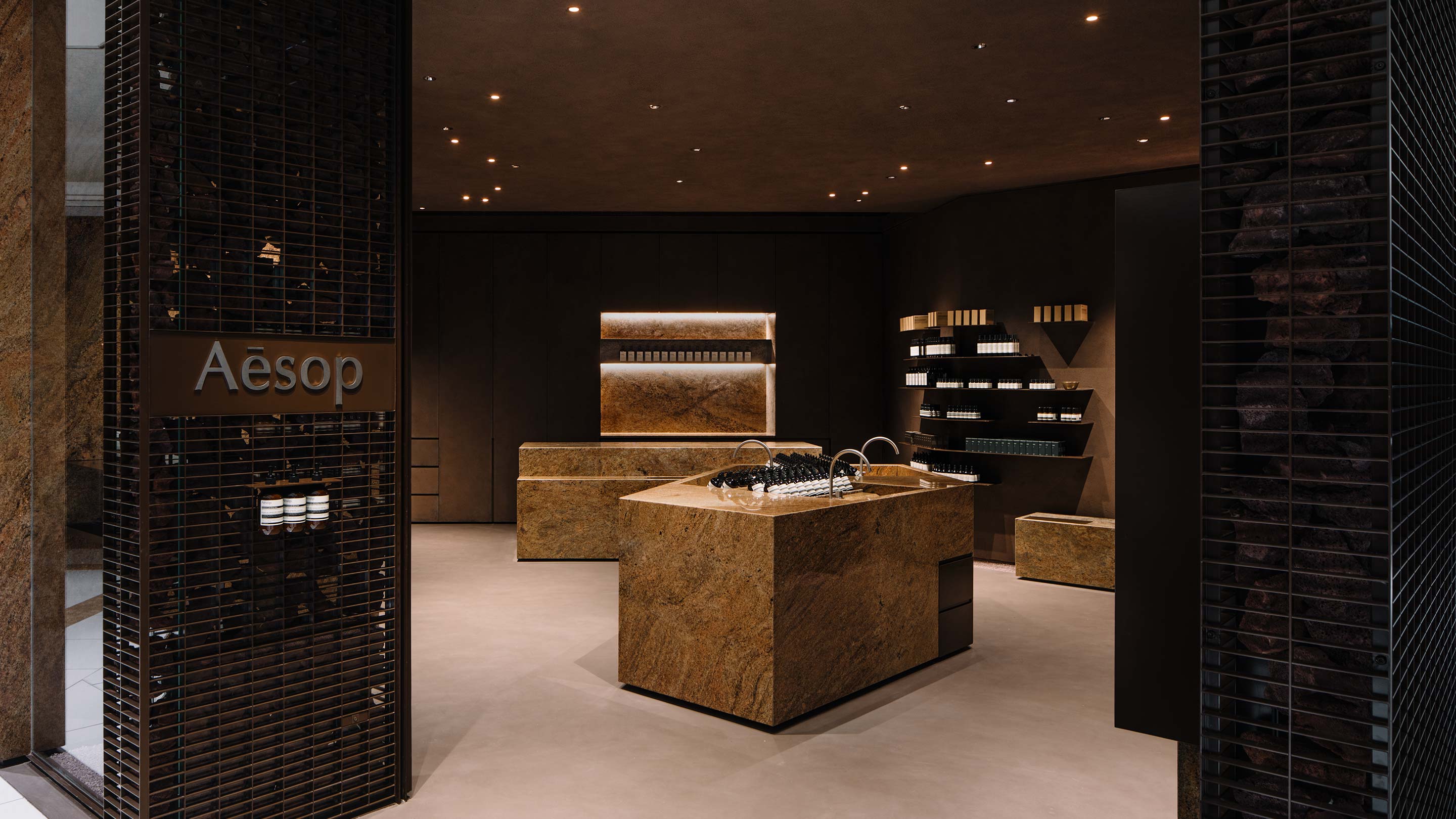 An exterior view of the store showing the steel grilled exterior that leads to a red rockstone customer service basin.