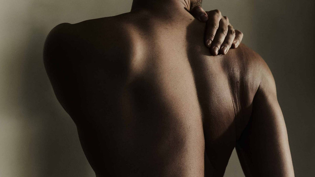 Person's bare back with one hand resting on their shoulder.