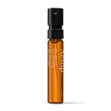 Small amber Aesop Eternal Karst sample vial with black cap on a white background.